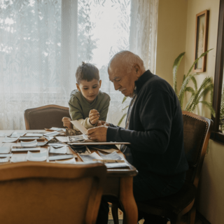 A grandfather and his grandson look at old photos together
