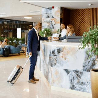 A man with a suitcase checks in with a hotel clerk