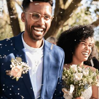 A just married bride and groom smiling beneath confetti